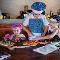 Load image into Gallery viewer, Three children in a kitchen with aprons and chef hats, preparing food.