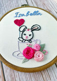 Load image into Gallery viewer, Embroidery hoop with a bunny in a teacup and flowers, personalized with 'Isabella'.