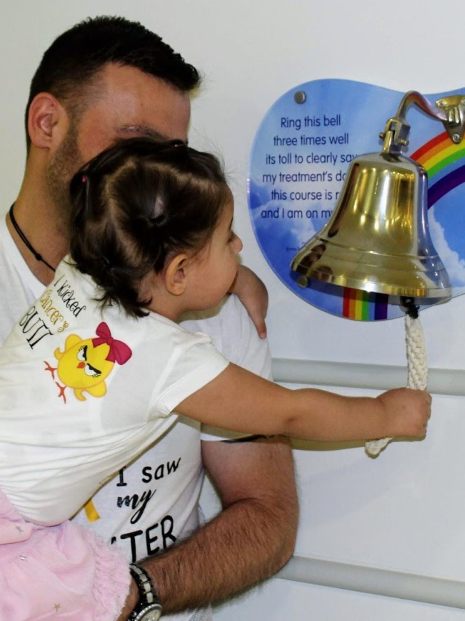A little girl ringing the end of treatment bell at Great Ormond Street Hospital in London