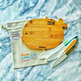 Load image into Gallery viewer, Wooden cutting board with 'Mumz Little Chefs' branding, accompanied by a knife and a branded bag on a marble surface.
