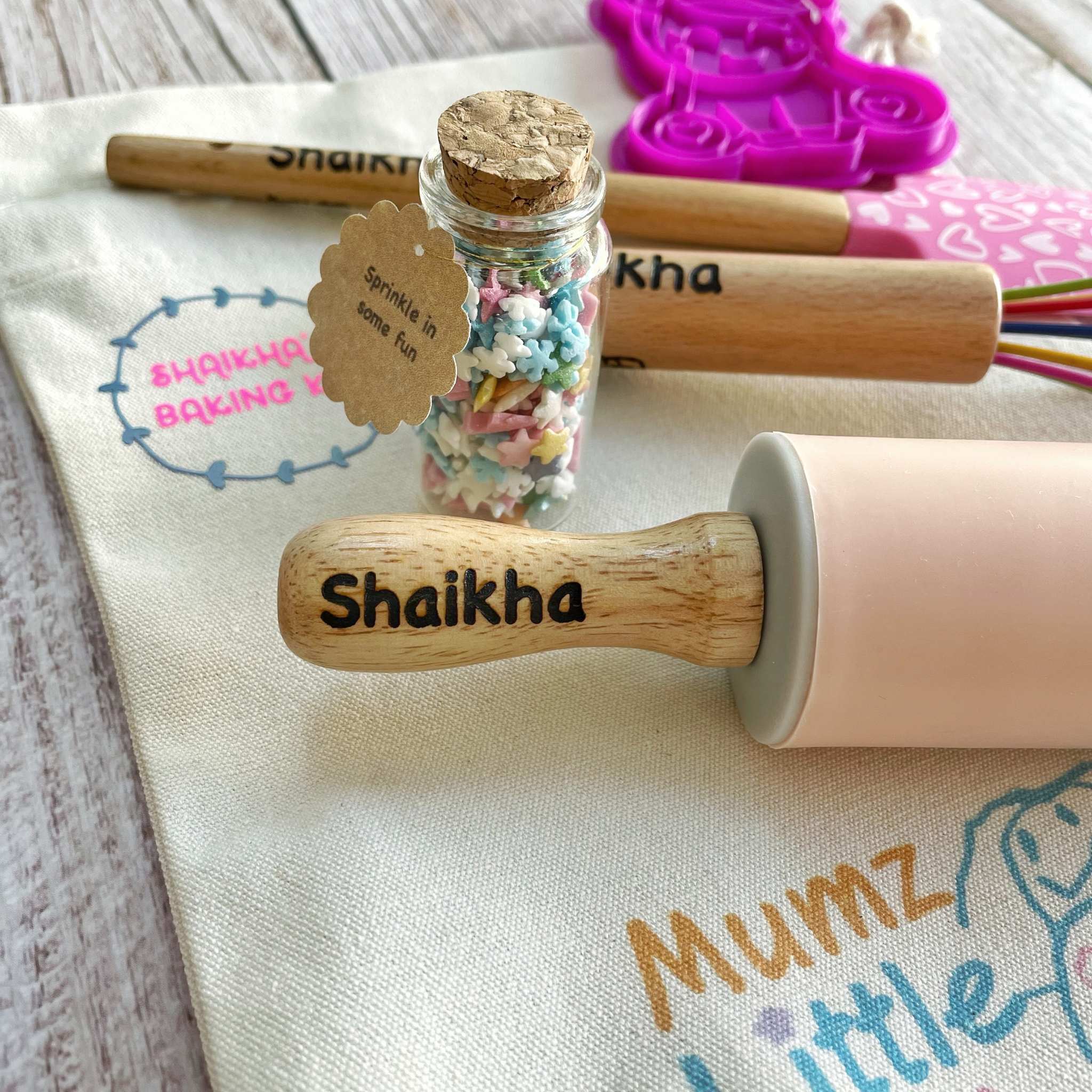Wooden stamp with 'Shaikha' engraved, surrounded by baking items on a table.