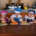 Load image into Gallery viewer, Three children in chef hats and aprons preparing food in a kitchen.
