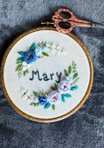Load image into Gallery viewer, Embroidery hoop with floral design and 'Mary' text on a textured surface
