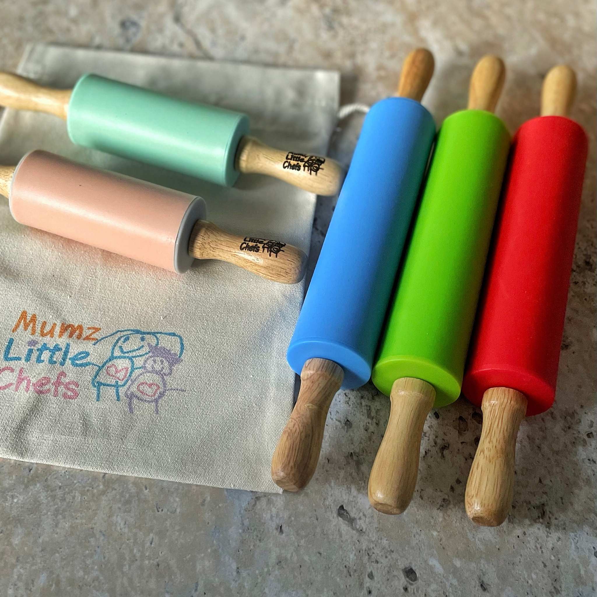 Set of colorful silicone rolling pins with wooden handles on a countertop.