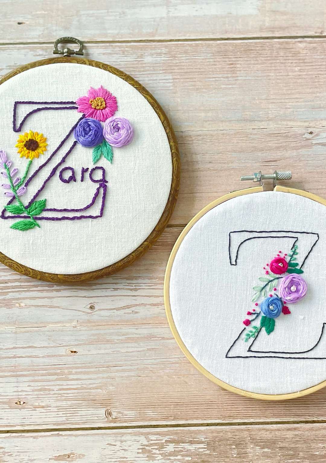 Two embroidery hoops with floral letter 'Z' designs on a wooden surface
