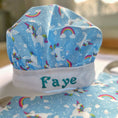 Load image into Gallery viewer, Blue chef's hat with unicorn and rainbow patterns and 'Faye' embroidered on it.
