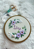 Load image into Gallery viewer, Embroidery hoop with floral design and 'Lina' text on a fluffy white surface.
