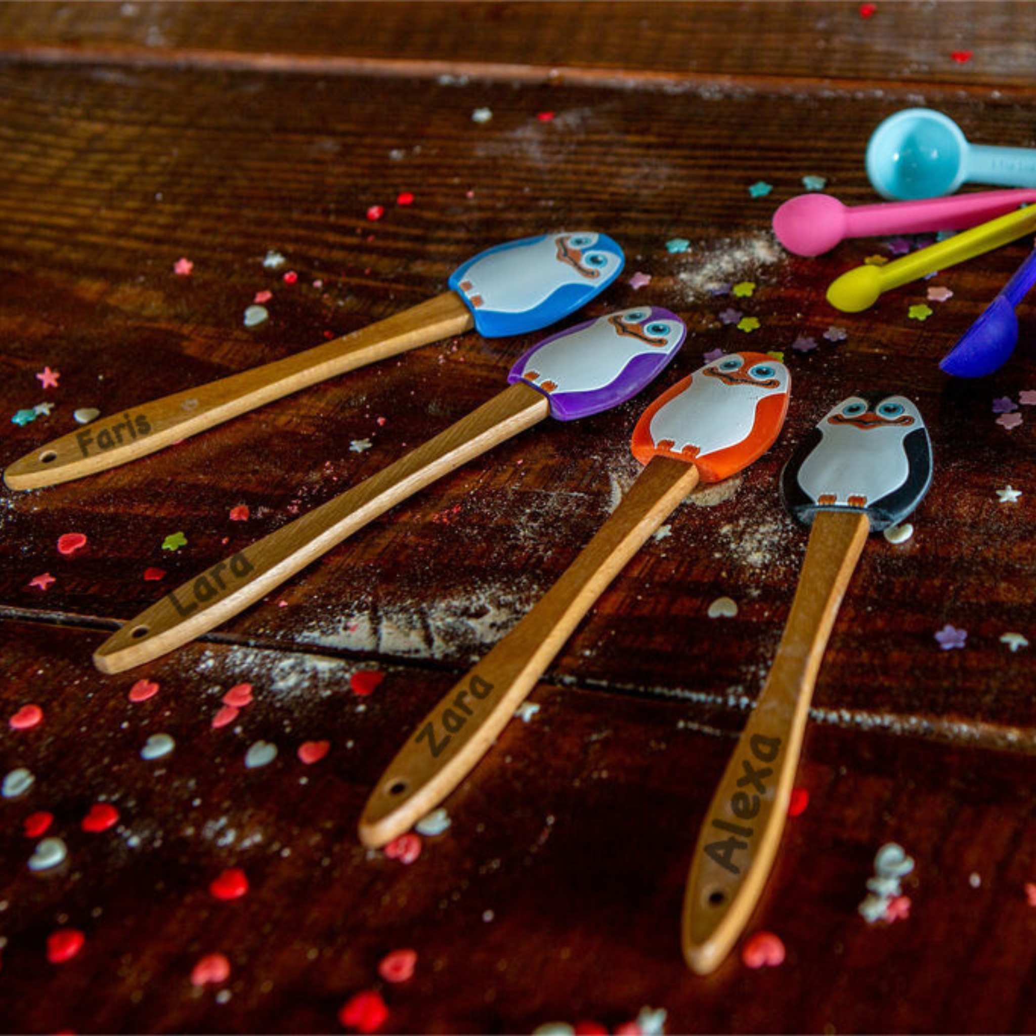 Set of wooden spoons with colorful owl handles on a wooden surface.